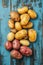 Variety of colorful potatoes arranged on a distressed blue wood surface