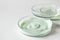 Variety cosmetic products in petri glass dishes on white background with selective focus. Body care