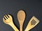 A variety of Cutlery and natural wood laid out on a black background.