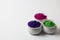 Variety of Different traditional colors filled in White earthen pots placed in white background. Holi Concept