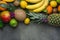 Variety of Different Tropical Summer Fruits. Pineapple Mango Coconut Citrus Oranges Lemons Apples Kiwi Bananas on Dark Stone