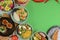 Variety of food dishes on bright green background. Table covere with food flat lay, top view, frame