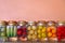 Variety of homemade vegetables and fruits pickled in glass jar with copy space over pink gold rose background