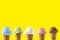 Variety of ice cream flavor in cones blueberry ,strawberry, green tea, chocolate and coconut setup on yellow background . Summer