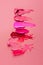 Variety of lipsticks with smudged stains on pink background for makeup beauty concept