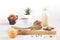 A variety of muffins with a cup of milk chocolate on a wooden board on a white background