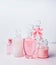 Variety of pink cosmetic product bottles and flowers standing on white pink background with bokeh. Skin care, cosmetic shop, sale