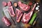 Variety of Raw Black Angus Prime meat steaks, tomahawk, t bone, club steak, rib eye and tenderloin cuts, on old dark rustic