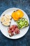 Variety slices of rye bread toast with fruits. Banana persimmon, kiwi, grape, sandwiches in a white plate on rusty background. Fl