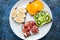 Variety slices of rye bread toast with fruits. Banana persimmon, kiwi, grape, sandwiches in a white plate on rusty background. Fl
