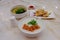 A variety of traditional dim sum dishes on dining table in restaurant. Porridge, and egg noodles in bowls, and pan fried turnip