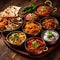 Variety traditional Indian dishes on the wooden table, selection of assorted spicy food.
