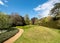 Variety of trees, grass and shrubs in nature with blue sky in the background. Photographed at Ascott House, Leighton Buzzard, UK