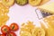 Variety of Types and Shapes of Dry Pasta Spaghetti Tagliatelle Fusilli Raw Tomatoes Bowl of Pesto Parmesan Cheese Top View Pink