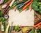 Variety of vegetables ingredients for soup or broth cooking around blank sheet of paper on rustic wooden background, top view.