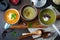 Variety of vegetarian soups cream of carrots, broccoli and cauliflower on a dark concrete background. Selective focus. Top view.