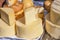 A variety of wheels of cheese seasoned with herbs for sale at the deli counter in the supermarket