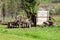 Various abandoned vintage retro rustic old dilapidated agricultural equipment with broken wooden tractor trailer left in backyard