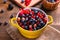 Various berries including blueberries, raspberries, blackberries currants and gooseberries in a yellow bowl on a brown woode