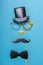 Various black photo booth props: cylinder hat, glasses, moustache, bow tie and nose in heart shape on blue background. Greeting