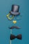 Various black photo booth props: cylinder hat, glasses, moustache, bow tie and nose in heart shape on blue background. Greeting