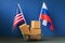 Various boxes in a food basket and two flags on a blue background, the concept of trade between USA and Russia