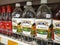 Various brands of cooking vinegar in commercial labeled bottles and displayed on shelves for sale.