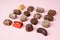 Various chocolate pralines on pink background. Collection chocolates candy. Assorted chocolates on pink