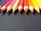 Various colored pencils over black background.