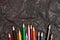 Various colored wooden pencils on black carbon paper background