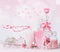 Various cosmetic glass bottles with pink ribbons and flowers standing on white pink background with bokeh. Skin care, cosmetic