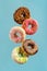 Various decorated doughnuts in motion falling on blue background