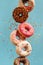 Various decorated doughnuts in motion falling on blue background