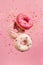 Various decorated doughnuts in motion falling on pink background