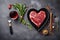 Various degrees of doneness of heart-shaped beef steak with spices, vegetables and a glass of wine on a dark stone