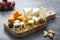 Various different types of cheese slices, cheese mix on wooden cutting board. Wine snack. Camembert, parmesan, brie cheese