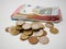 Various Euro coins and banknotes on a white desk. Notes and coins of various denominations.