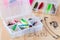 Various fishing lures in plastic box and fishing accessories on wooden background, horizontal