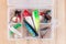 Various fishing lures in plastic box on wooden background, horizontal, top view