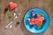 Various fresh fruits and berries on a plate on a brown stone or slate background - watermelon, blackberries, plums and grapes.