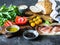 Various fresh ingredients for making sandwiches - vegetables, bread, prosciutto, olive oil and curd cheese on dark background