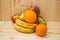 Various fruits apples, bananas, oranges, pomegranates on natural wooden background