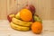 Various fruits apples, bananas, oranges, pomegranates on natural wooden background