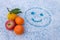 Various fruits lie on a snowy table with a painted face smiling