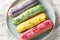 Various glazed sweet eclairs with with berry tastes closeup on plate. Horizontal top view