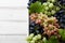 Various grapes with leaves in white wooden tray