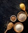 Various groats, cereals. Different types of groats in bowls and on a spoons on a black background, top view.