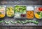 Various Healthy lunch boxes in plastic package and green measuring tape on rustic background, top view