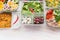 Various Healthy salad bowls in plastic package for diet lunch on white wooden background