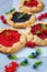 Various homemade tarts with fresh blueberries, raspberries, red currants on the gray background. Vegetarian berries galette